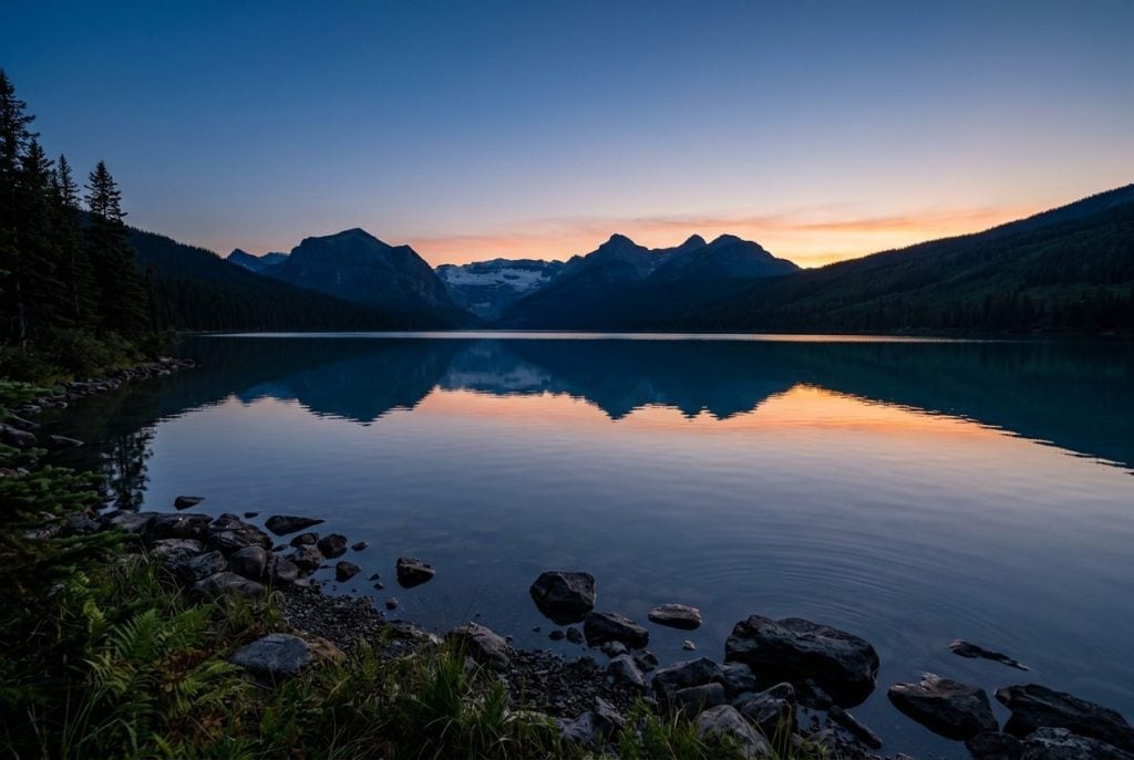 Calm mountain lake reflecting a twilight sky with silhouetted hills